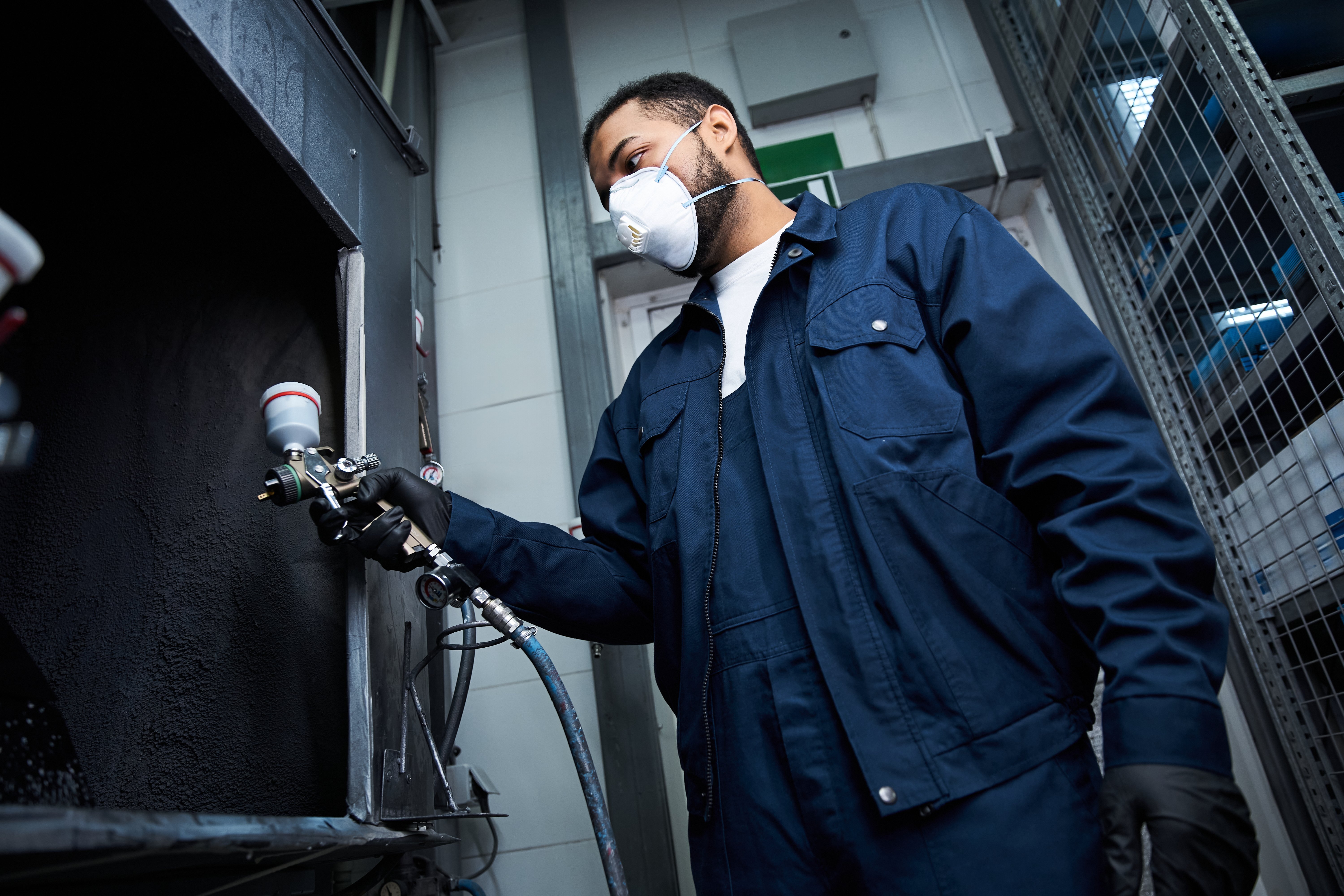 A skilled mechanic works diligently on car maintenance using specialized tools in a service center.