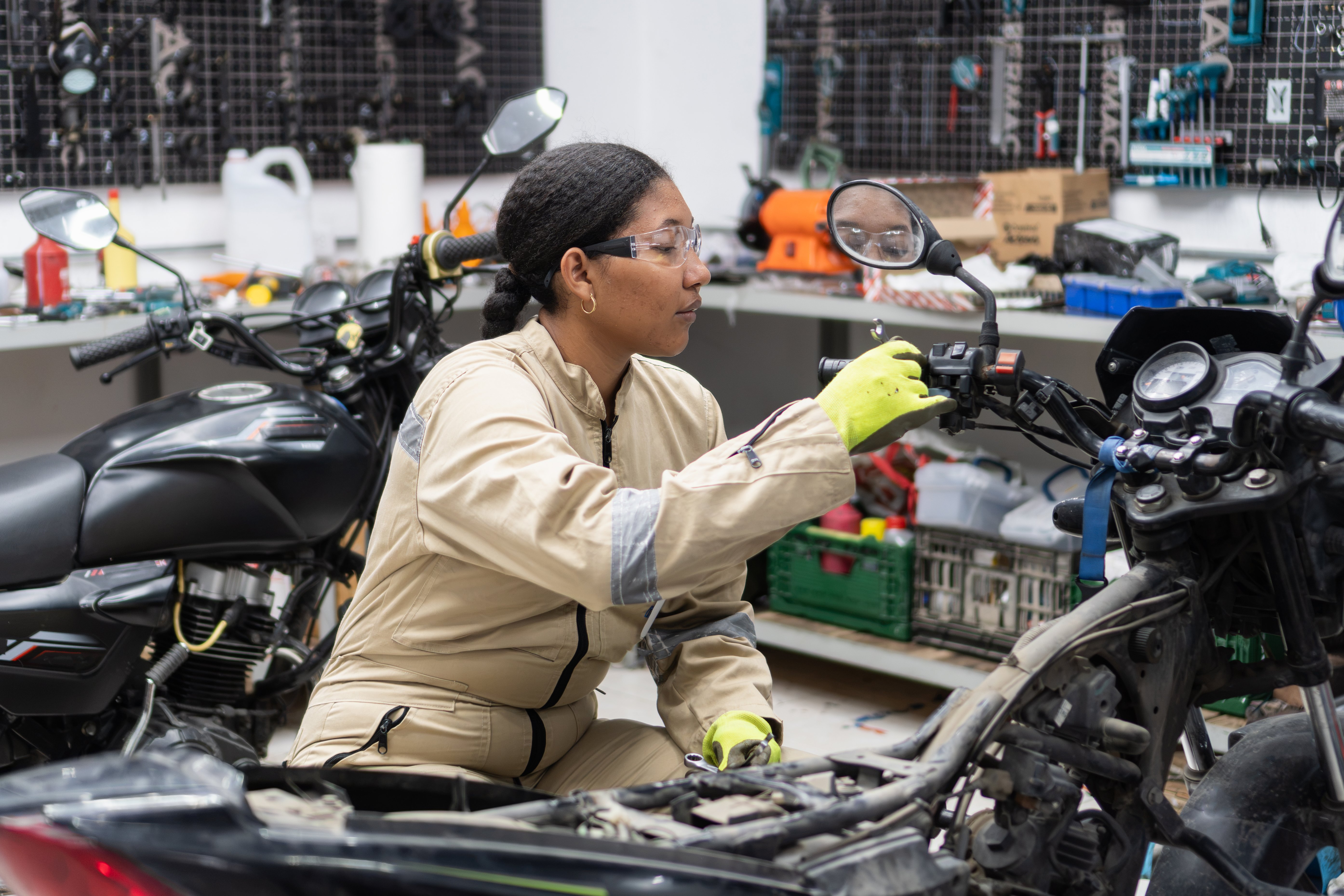 Woman mechanic wearing safety glasses and gloves working on a motorcycle engine